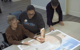 A staff member and two others gather around a table reviewing documents together, reflecting the attentive, community-centered approach to senior care in Acworth, GA.
