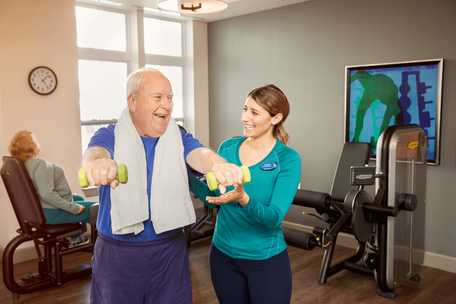 physical therapist in teal shirt helping older patient