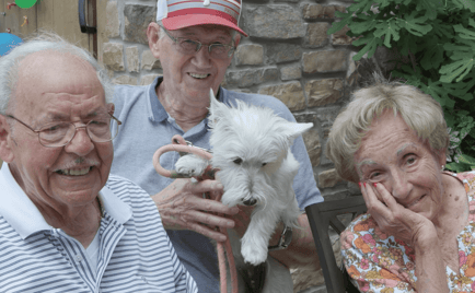 Residents smiling, holding a dog