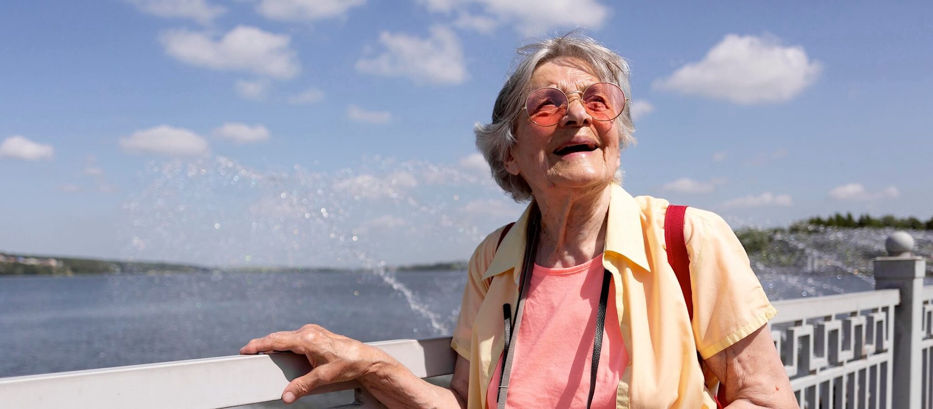 Senior traveler holding camera with sunglasses on admiring the sunny day