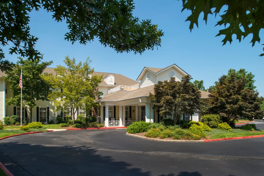 The well-maintained exterior of Arbor Terrace Athens, recognized as one of the best senior living communities in Athens, GA, featuring classic white architectural details, a welcoming entrance, and manicured grounds on a clear, sunny day.