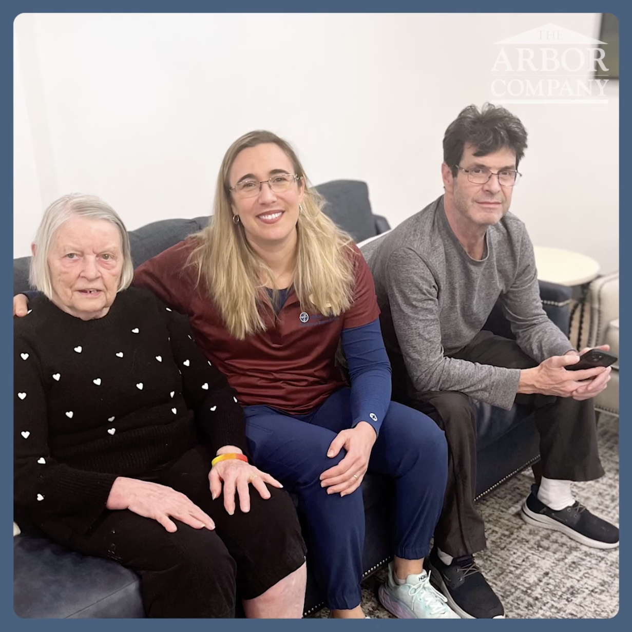 Resident, staff member, and family member sitting on a couch 
