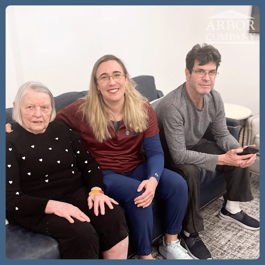 Resident, staff member, and family member sitting on a couch 
