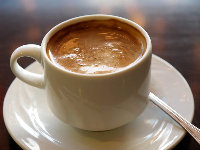 A close-up of a freshly brewed cup of coffee on a warm wooden table, reflecting the inviting dining experience at senior living near Carrollwood, FL.