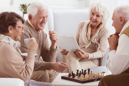 Senior group playing chess smiling