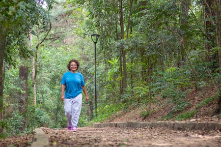 A resident enjoys a peaceful walk along a wooded trail, reflecting the active senior lifestyle and access to forest preserves near Glenview, IL.
