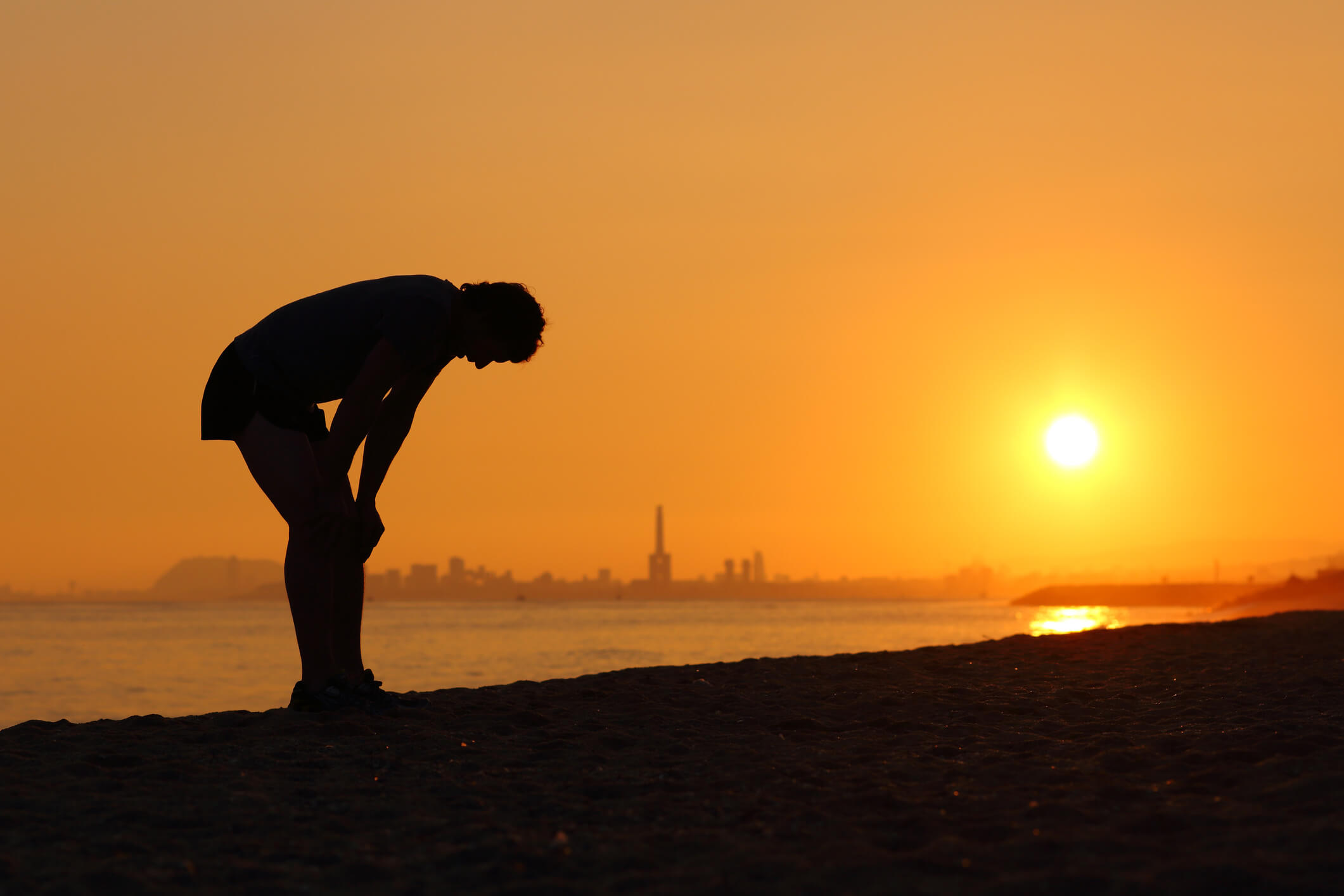 A man pauses to catch his breath against a glowing sunset over the water, capturing the active, scenic lifestyle near senior living near beaches in Clearwater, FL.