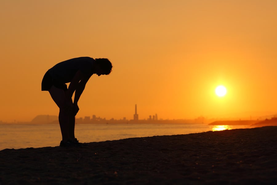 A man pauses to catch his breath against a glowing sunset over the water, capturing the active, scenic lifestyle near senior living near beaches in Clearwater, FL.