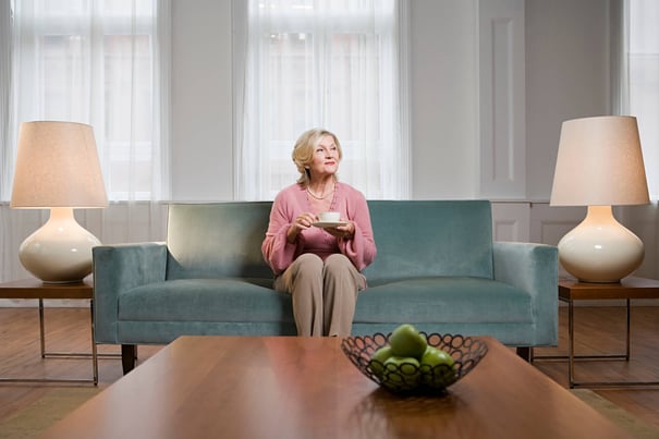 a senior lady sitting on a sofa and enjoying her tea