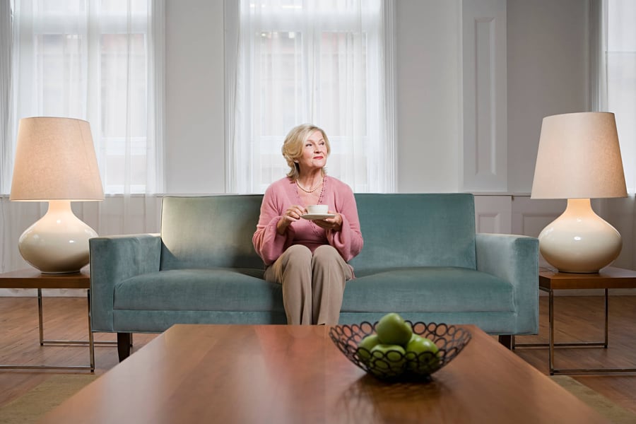 a senior lady sitting on a sofa and enjoying her tea