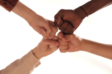 Four hands come together in a unified fist bump, symbolizing the compassionate teamwork and dedicated senior care that defines the Arbor Terrace Morris Plains assisted living community in Morris Plains, NJ.