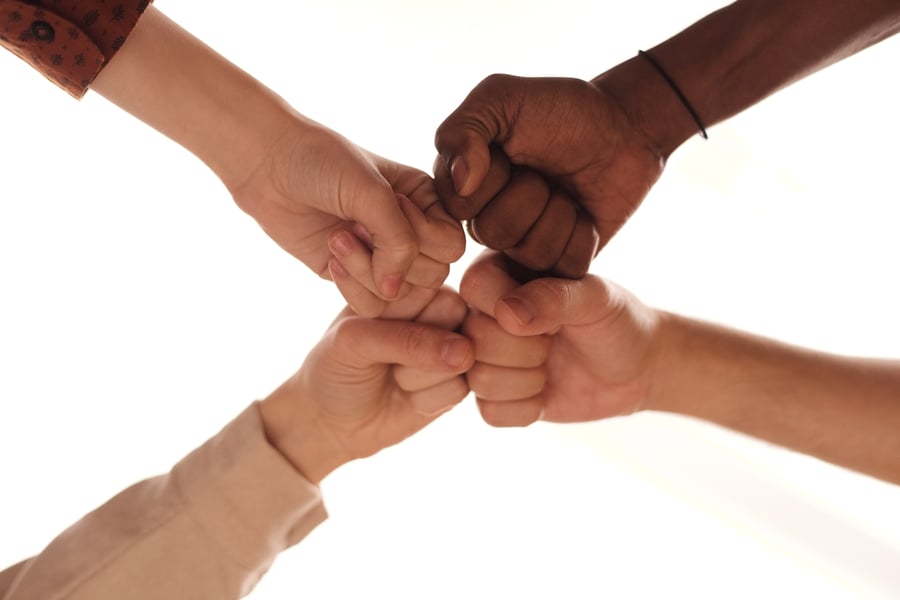 Four hands come together in a unified fist bump, symbolizing the compassionate teamwork and dedicated senior care that defines the Arbor Terrace Morris Plains assisted living community in Morris Plains, NJ.