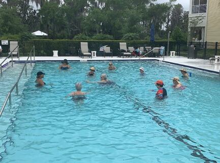 Residents enjoy a refreshing group water exercise class in the outdoor pool, highlighting the active, resort-style senior living in Citrus Park, FL.
