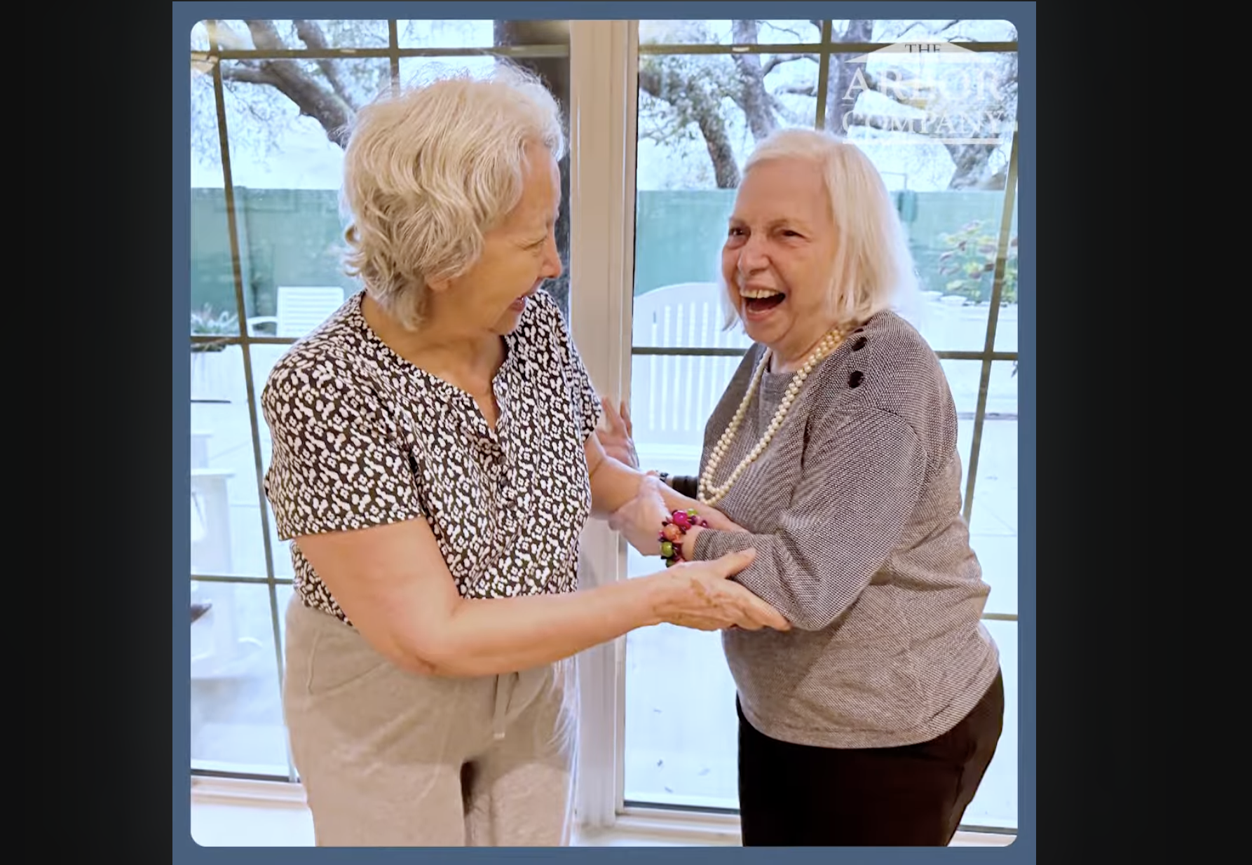 Two residents share a joyful laugh together by a sunlit window, reflecting the warm friendships at senior living in Citrus Park, FL.
