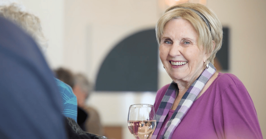 Opus East Memphis resident smiling holding a glass of wine