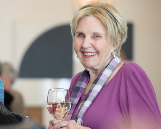 Senior resident holding a wine glass and smiling