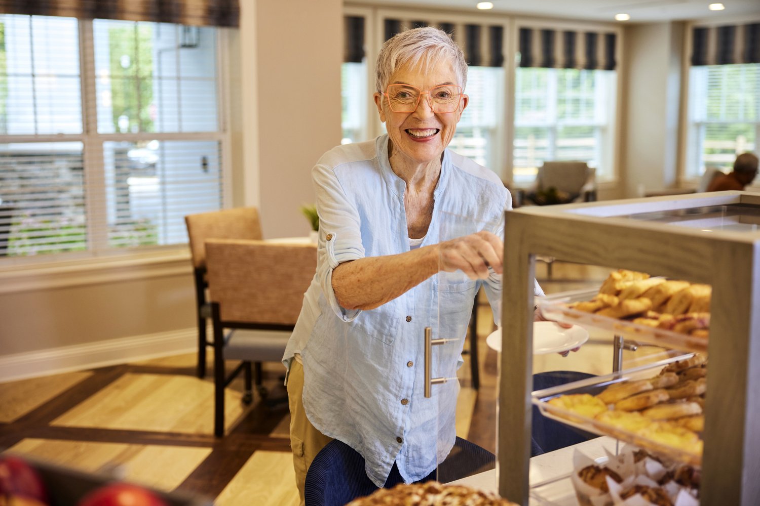 Senior woman grabbing pastry in the bistro