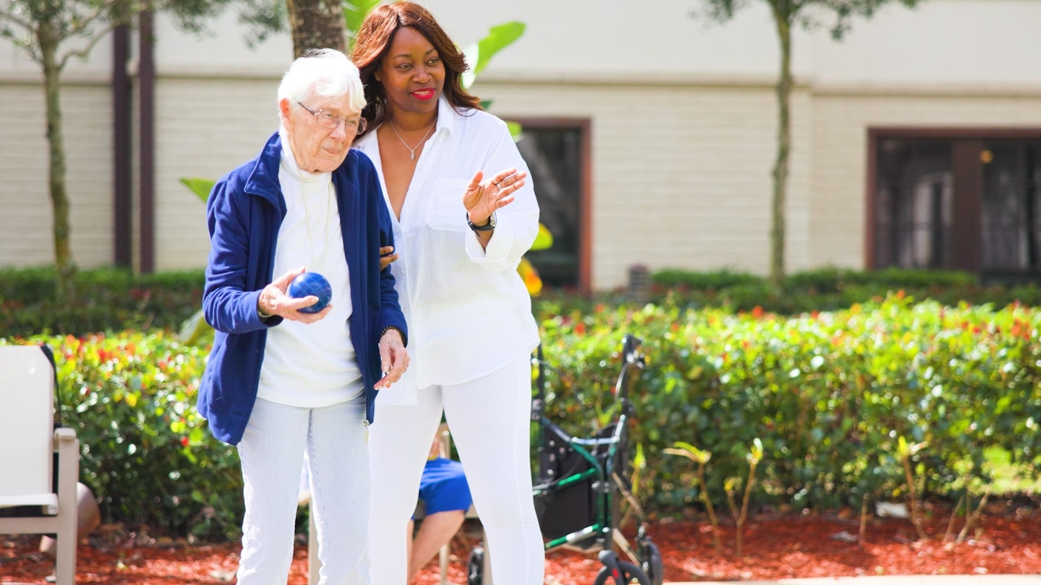 A senior lady and female employee playing bocce at the garden