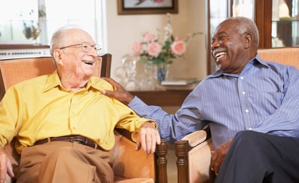 two senior men enjoying each other's company while hanging out at a senior living community living room