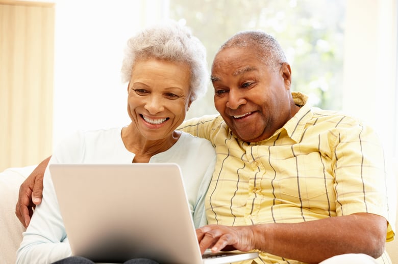Couple smiling and embracing sitting a looking at a computer