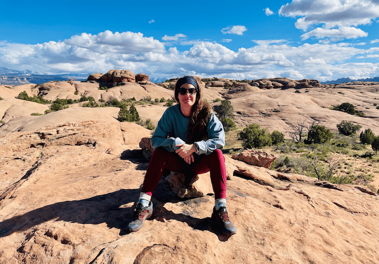 A staff member sits on rocky desert terrain under a bright blue sky — reflecting the adventurous spirit behind the dedicated senior care team at Arbor Terrace Lakeway TX.