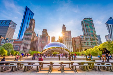 The sun sets behind Chicago skyscrapers and the iconic Bean sculpture in Millennium Park, showcasing the vibrant city life near this senior living community in Park Ridge, IL.