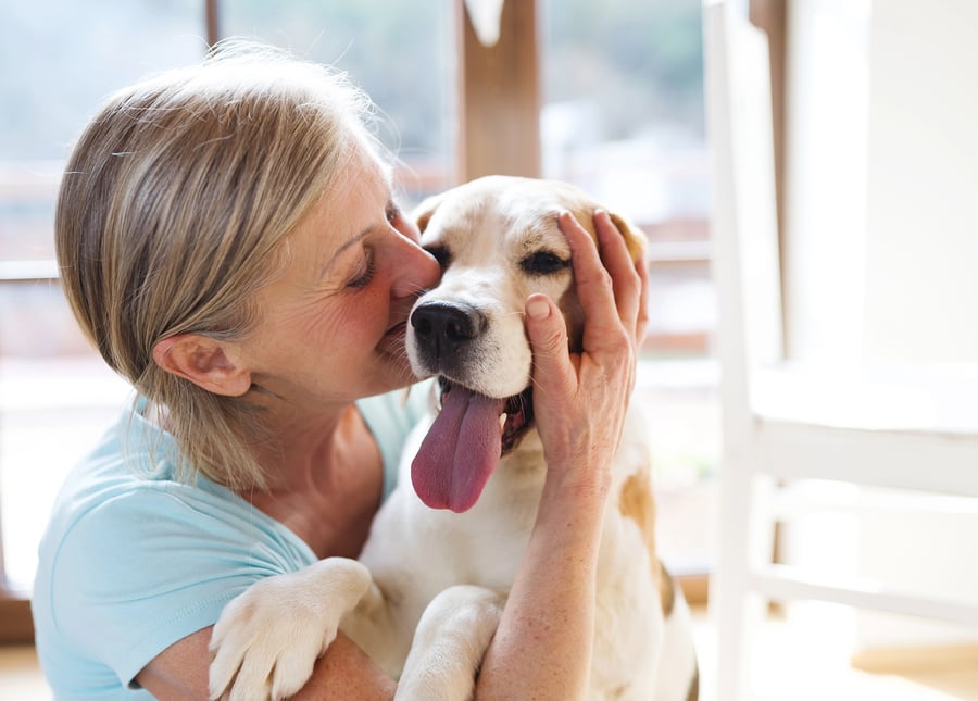 A resident tenderly nuzzles her dog indoors, reflecting the warm, pet-friendly environment at Mirabelle, a welcoming assisted living community in Miami, FL where beloved companions are always part of the family.