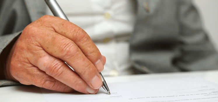 A close-up of a hand signing a document, representing the straightforward move-in process at a trusted assisted living community in Suwanee, GA.
