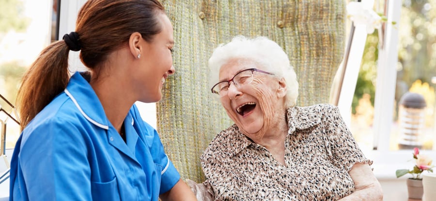 A caregiver and an older adult share a hearty laugh together, capturing the joyful, compassionate senior care relationships at the heart of Arbor Terrace Morris Plains, NJ.