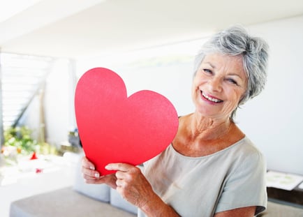 a senior lady holding a valentine's heart cutout
