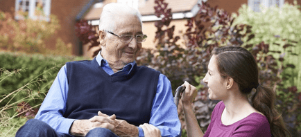 senior man in wheelchair smiling at caregiver