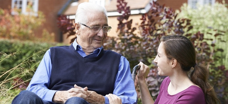 senior man in wheelchair smiling at caregiver