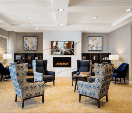 An elegant lounge features a cozy fireplace and wingback chairs, showcasing the award winning memory care communities in Glenview, IL.
