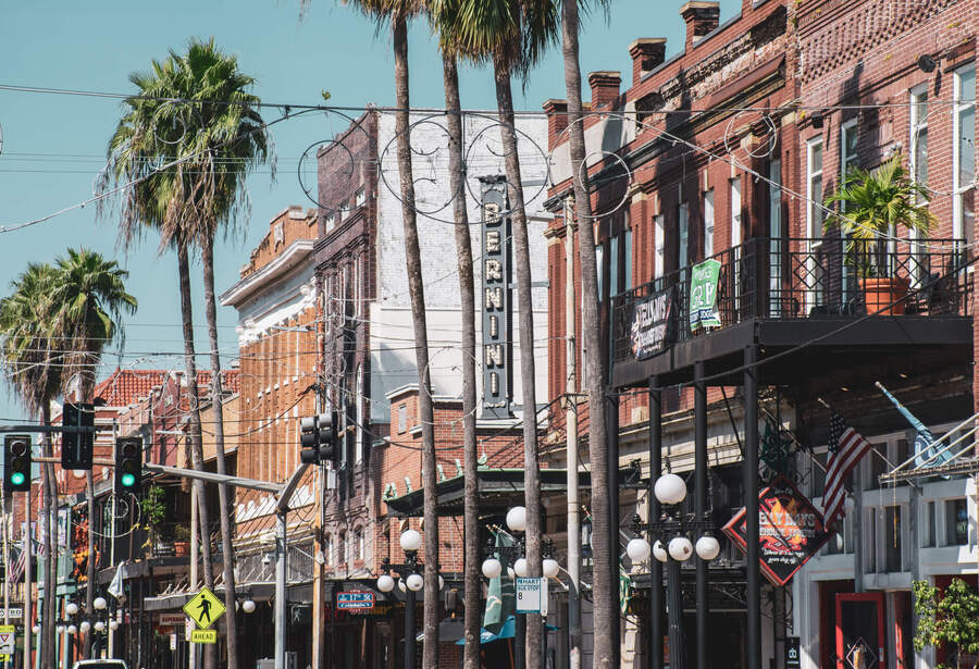 A vibrant street scene in Tampa's historic Ybor City district, lined with palm trees and classic brick storefronts, showcasing the lively surroundings near senior living in Tampa, FL.