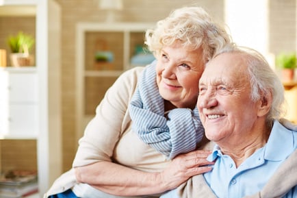 Two people share a warm, tender embrace in a bright and cozy living space, reflecting the loving connections at a retirement living community in Suwanee, GA.