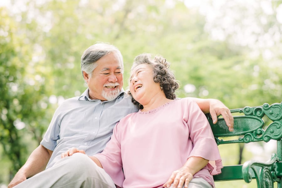 Senior Resident Couple Smiling and Laughing on a bench