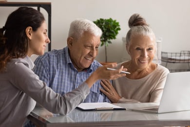 Family sitting around a table smiling looking at a computer with a clipboard and pen