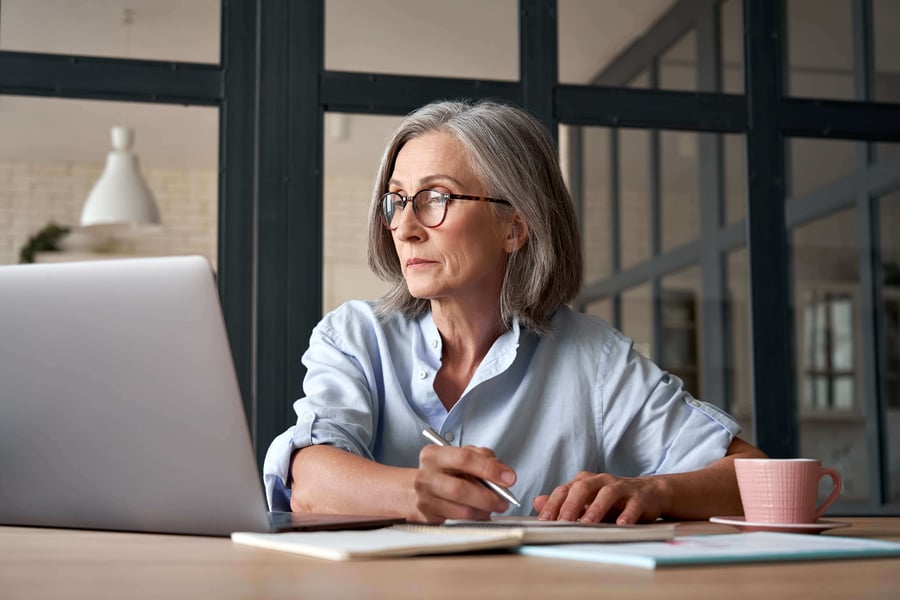 Elderly woman assessing independent living costs from a laptop computer