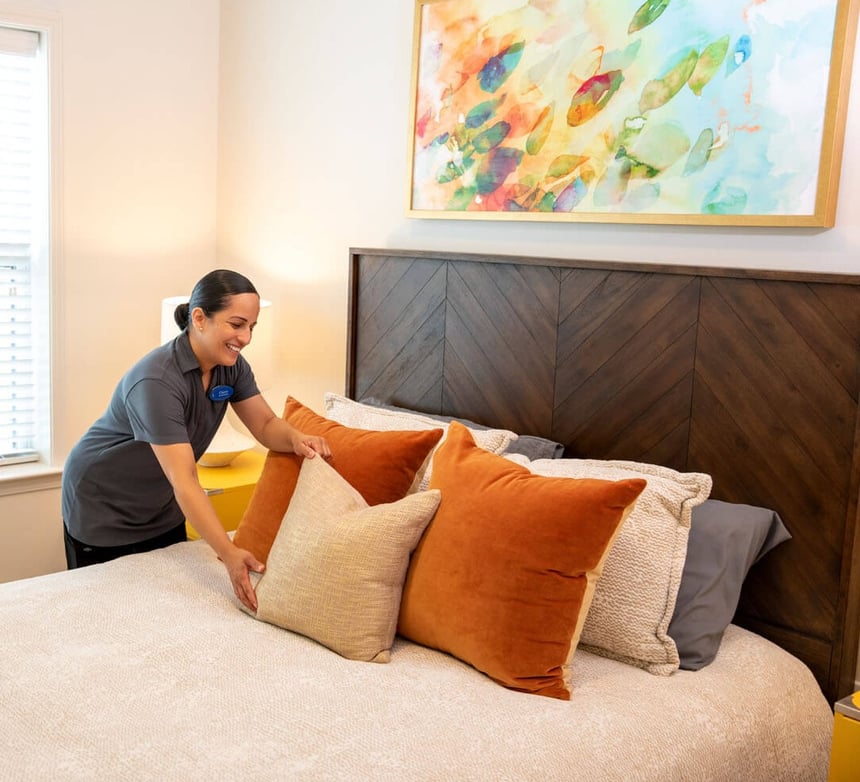 a female staff member fixing the pillows on a bed