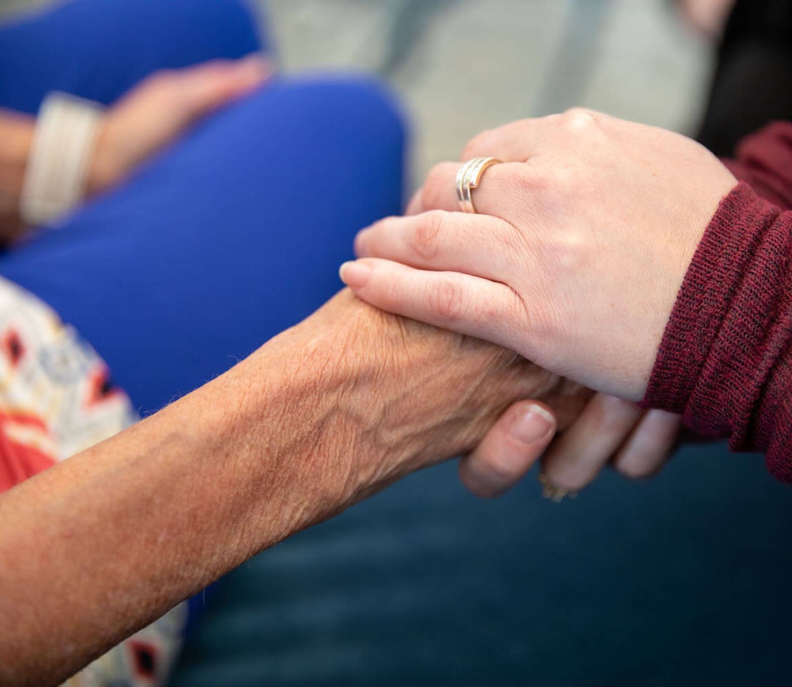 Caregiver holding senior's hand showing support