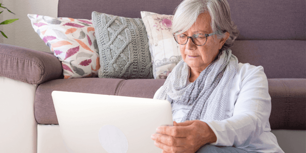 elderly woman sitting on the floor using a laptop computer