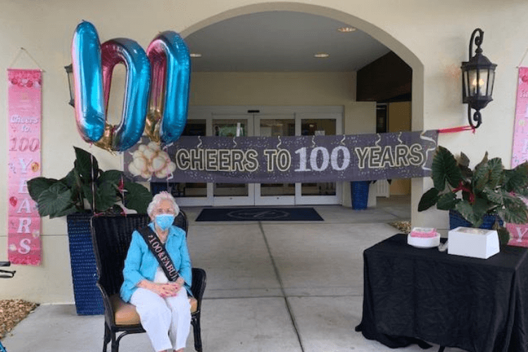 A resident celebrates a remarkable 100th birthday milestone with festive decorations at the entrance, highlighting the joyful community life at senior living in Citrus Park, FL.