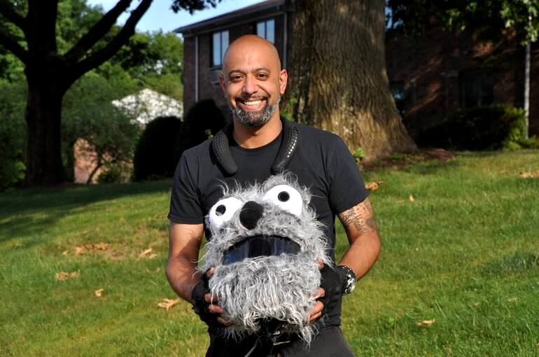 A smiling entertainer holds a fun puppet character outdoors, bringing lively and engaging programming to residents at Arbor Terrace Morris Plains, a vibrant assisted living community in Morris Plains, NJ.