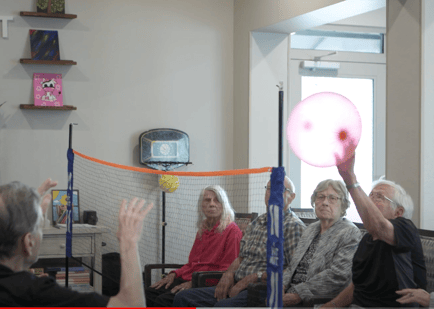 A group of seniors plays an indoor balloon volleyball game at Arbor Terrace Lakeway — person-centered, engaging activities that define individuality-focused memory care Lakeway TX.