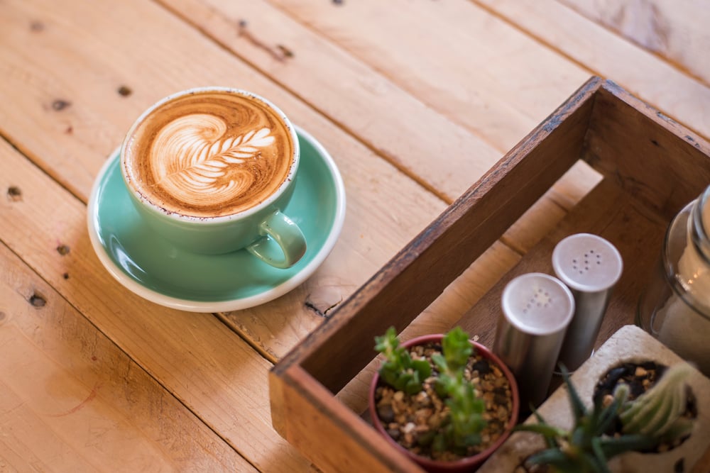 A beautifully crafted latte art coffee served on a rustic wooden tray, evoking the cozy café culture and vibrant dining scene near Arbor Terrace Lakeway, a senior living community in Lakeway, TX.