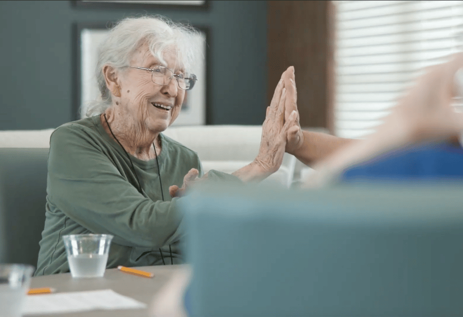 A senior laughs warmly while sharing a high-five during the Connections Program at Arbor Terrace Lakeway — personalized assisted living Lakeway TX focused on wellness and meaningful engagement.