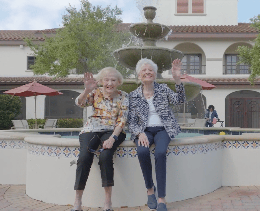 Seniors sitting by the fountain waving to the camera 