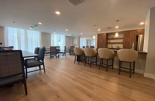 A bright, open common area in Mirabelle's memory care neighborhood in South Miami, FL, featuring warm wood floors, natural light, and thoughtfully arranged seating designed to create a calm, comfortable space.