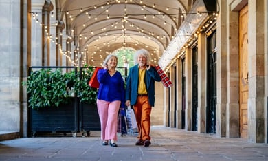 Two residents stroll through a charming covered walkway near Dadeland Mall, just minutes from this senior living community in Miami, FL, where shopping and social outings are always close by.