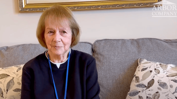 A resident speaks warmly from a cozy sofa at Arbor Terrace Morris Plains, reflecting the comfortable, personalized assisted living experience available in Morris Plains, NJ.